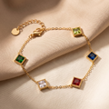 Gold bracelet with colorful gemstones on a beige fabric background