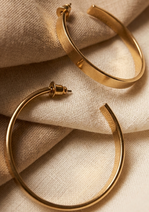 Gold hoop earrings on a beige fabric background