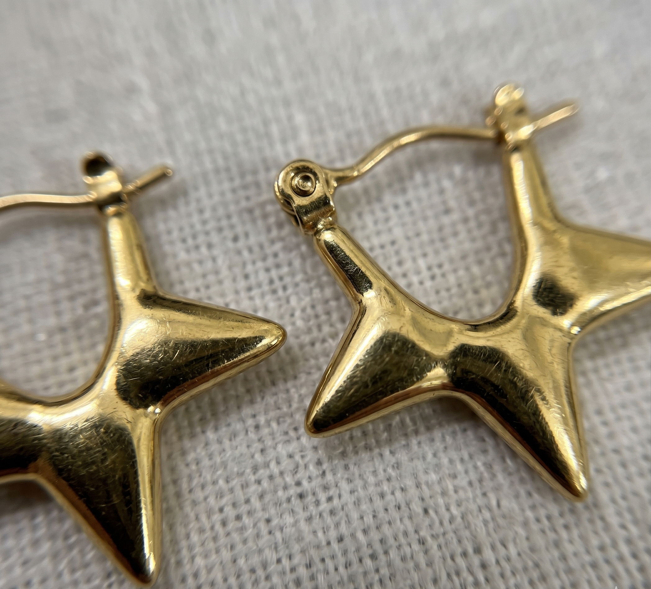 Gold star-shaped earrings on a textured gray background