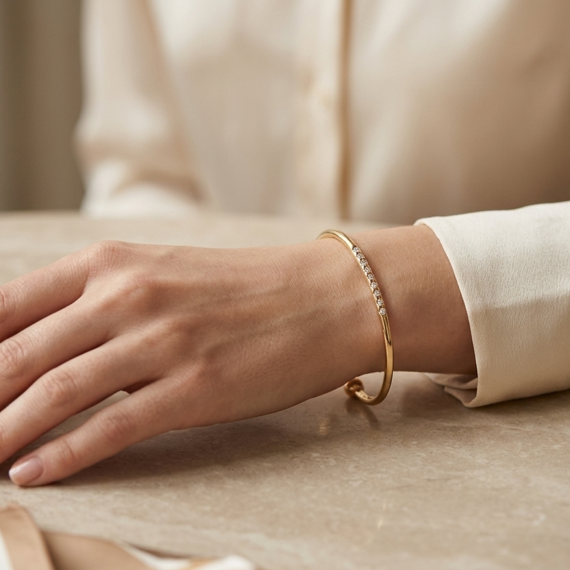 Hand wearing a gold bracelet on a table with a bowl and tissue paper.