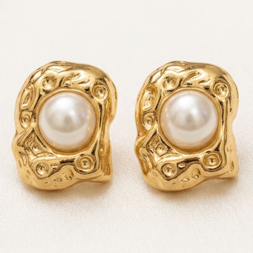 Gold earrings with pearl centers on a light background