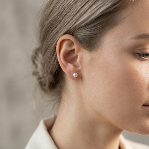 Close-up of a woman wearing a diamond earring with a neutral background