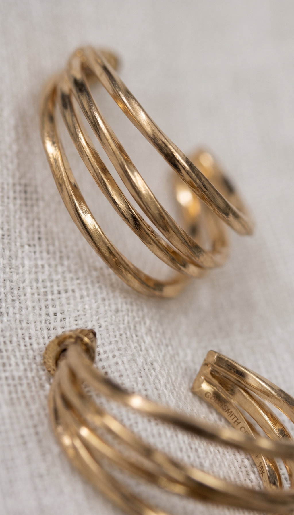 Gold hoop earrings on a light fabric background