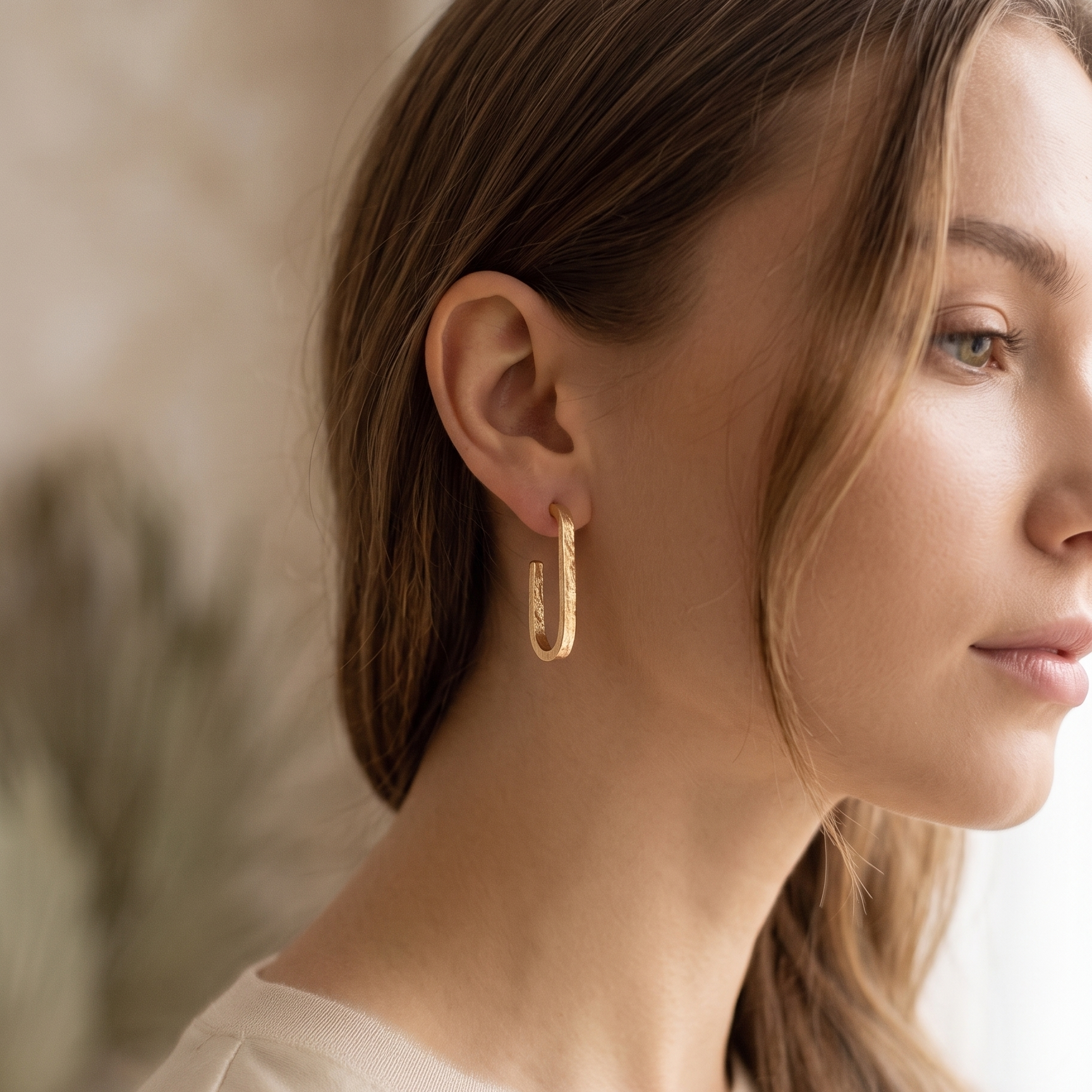 Woman wearing gold hoop earrings with a neutral background