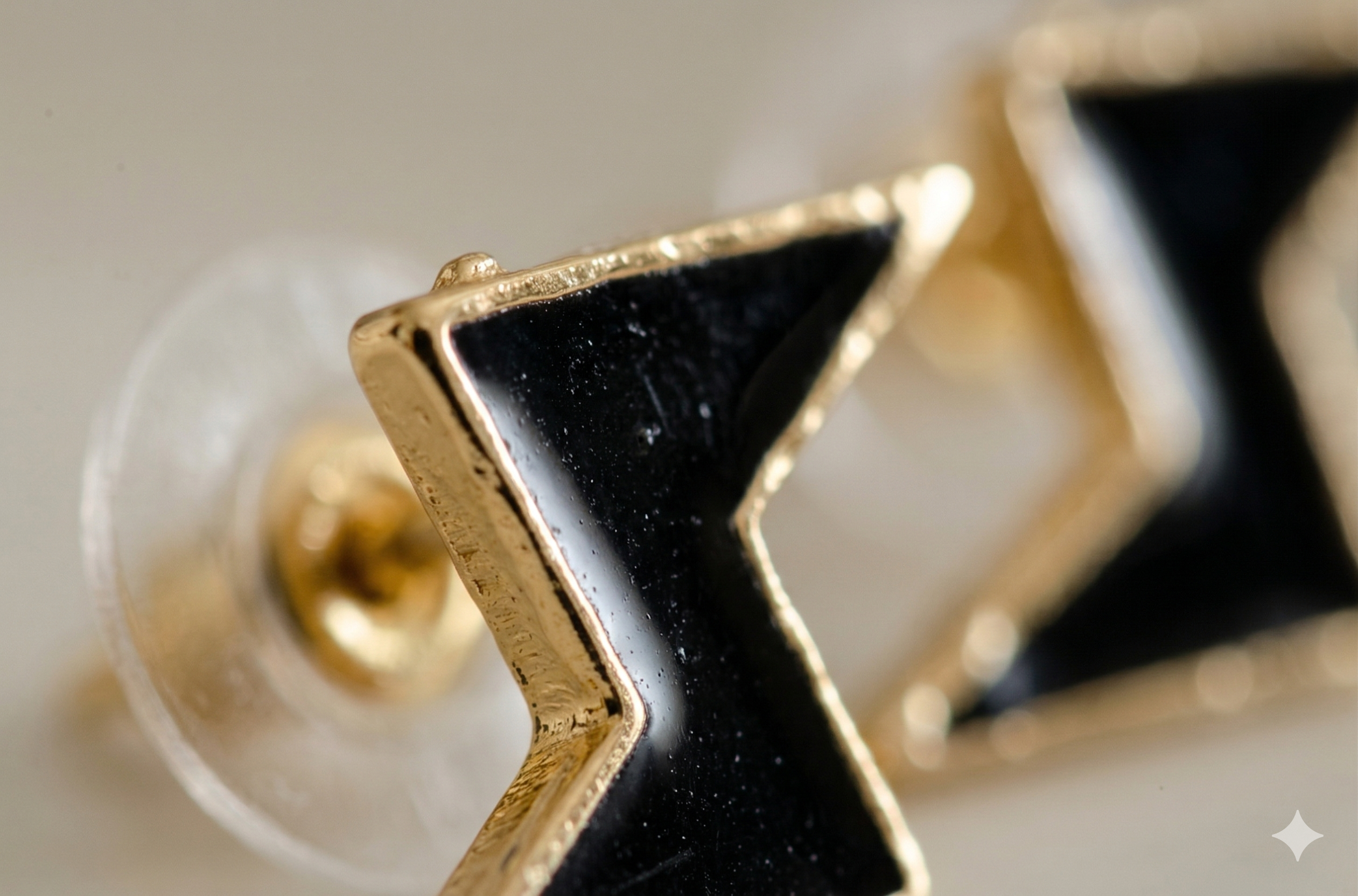 Close-up of black and gold geometric earrings on a light background