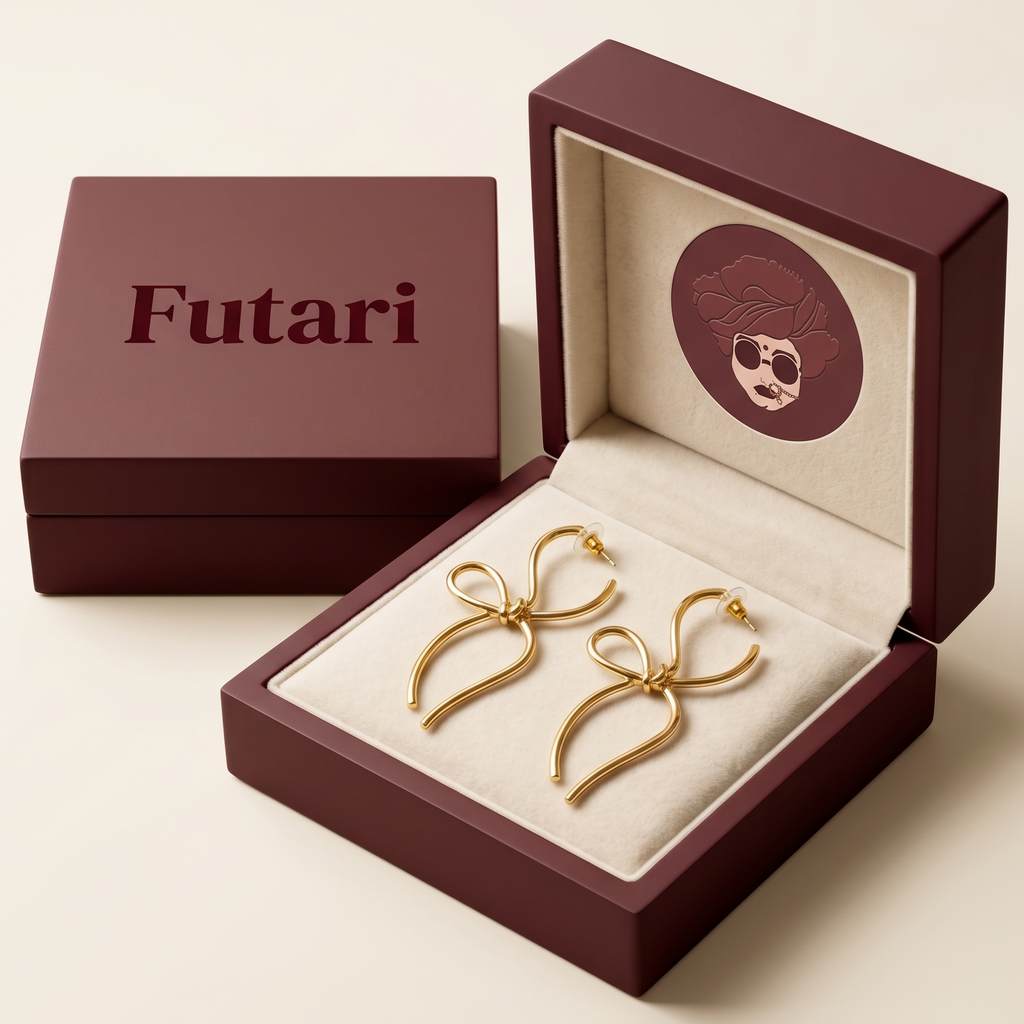 Gold bow-shaped earrings in an open maroon box with 'Futari' branding.