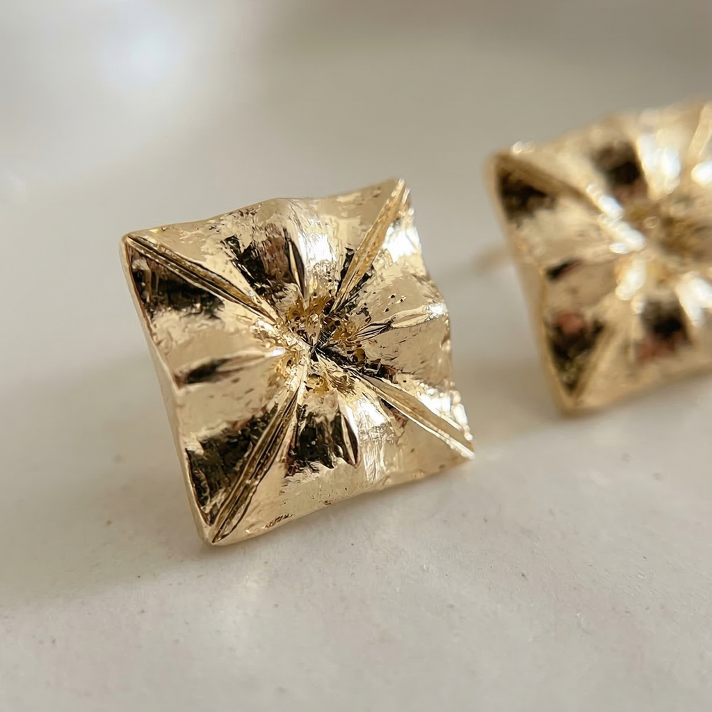 Gold pyramid-shaped earrings on a light background