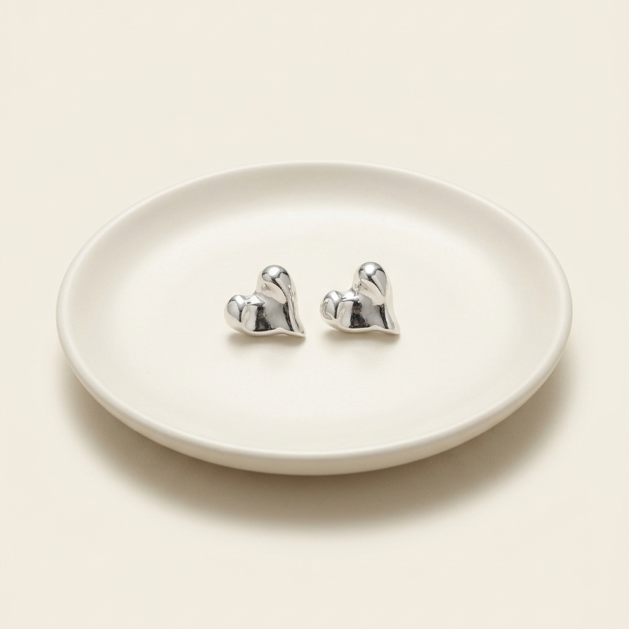 Pair of silver earrings on a white dish with a white background