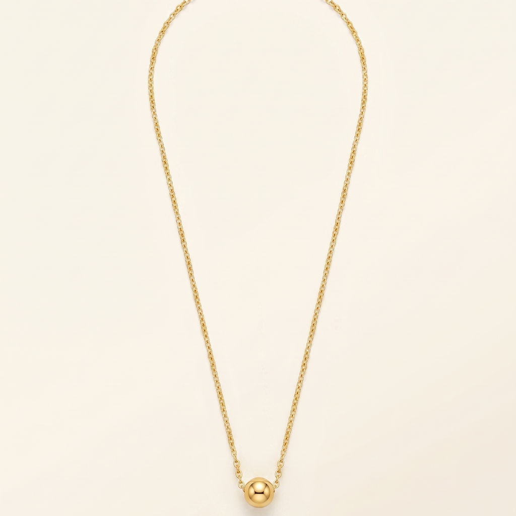 Gold necklace with a single pearl pendant on a beige background