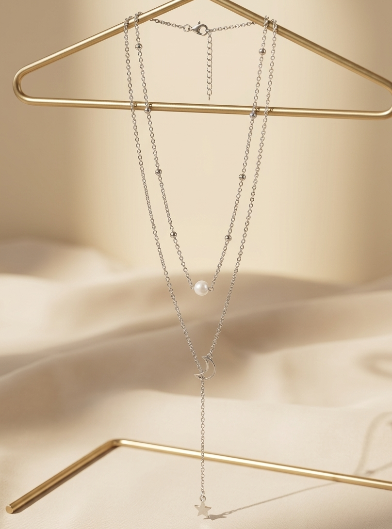 Layered necklace with pearl and starfish pendant on a gold hanger against a beige background