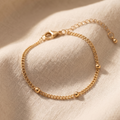 Gold chain bracelet on a beige fabric background