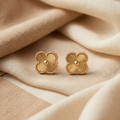 Pair of gold earrings on beige fabric