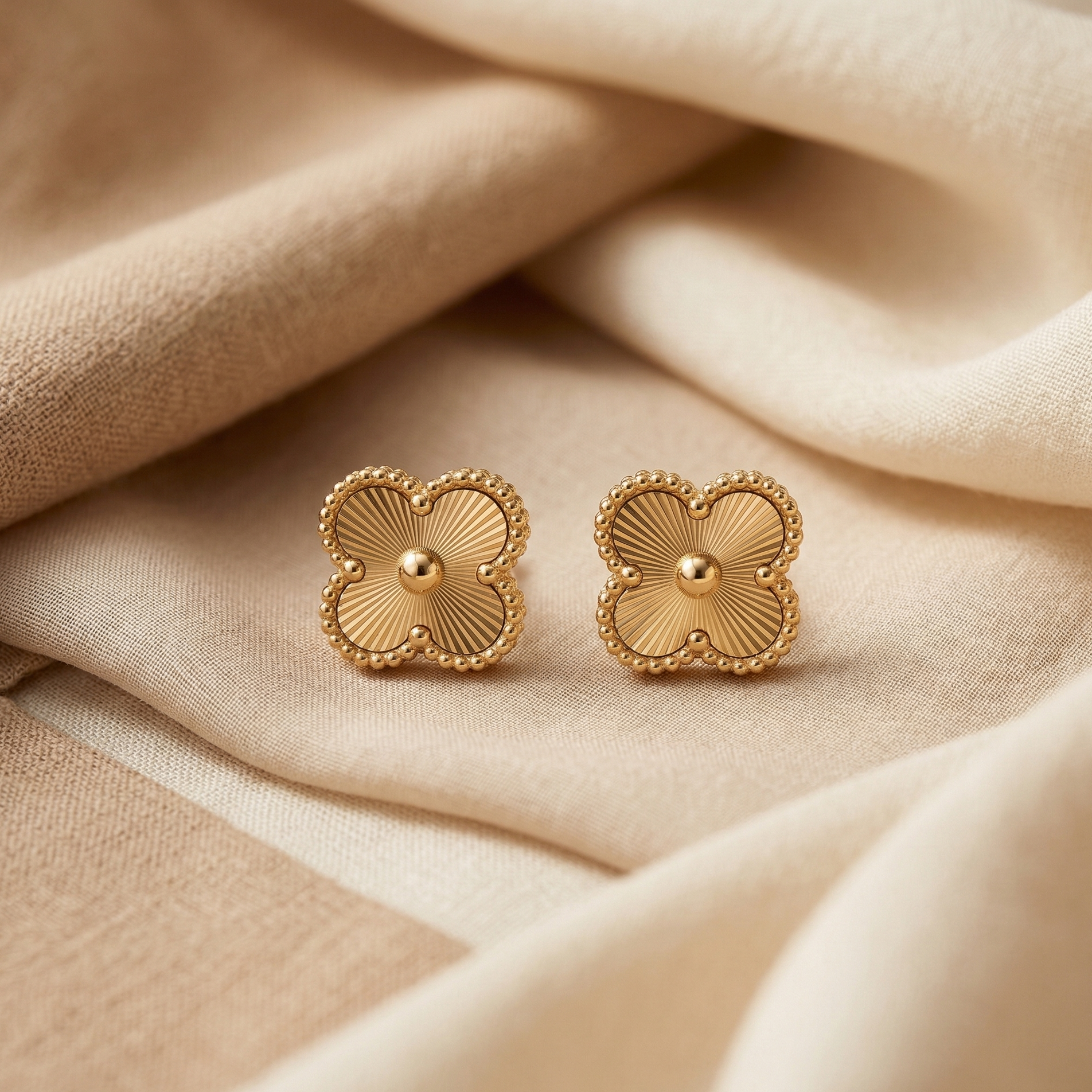 Pair of gold earrings on beige fabric