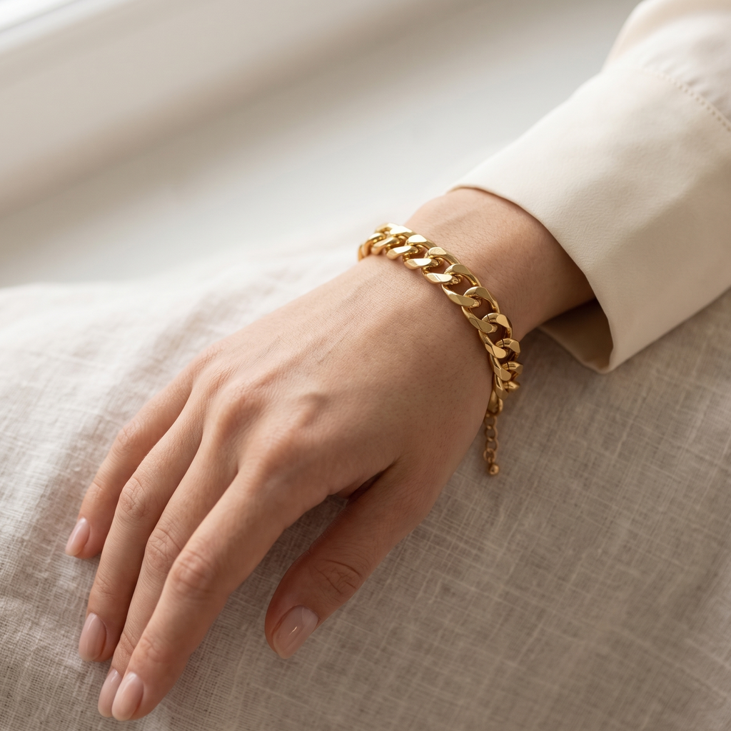 Gold chain bracelet on a wrist with a neutral background
