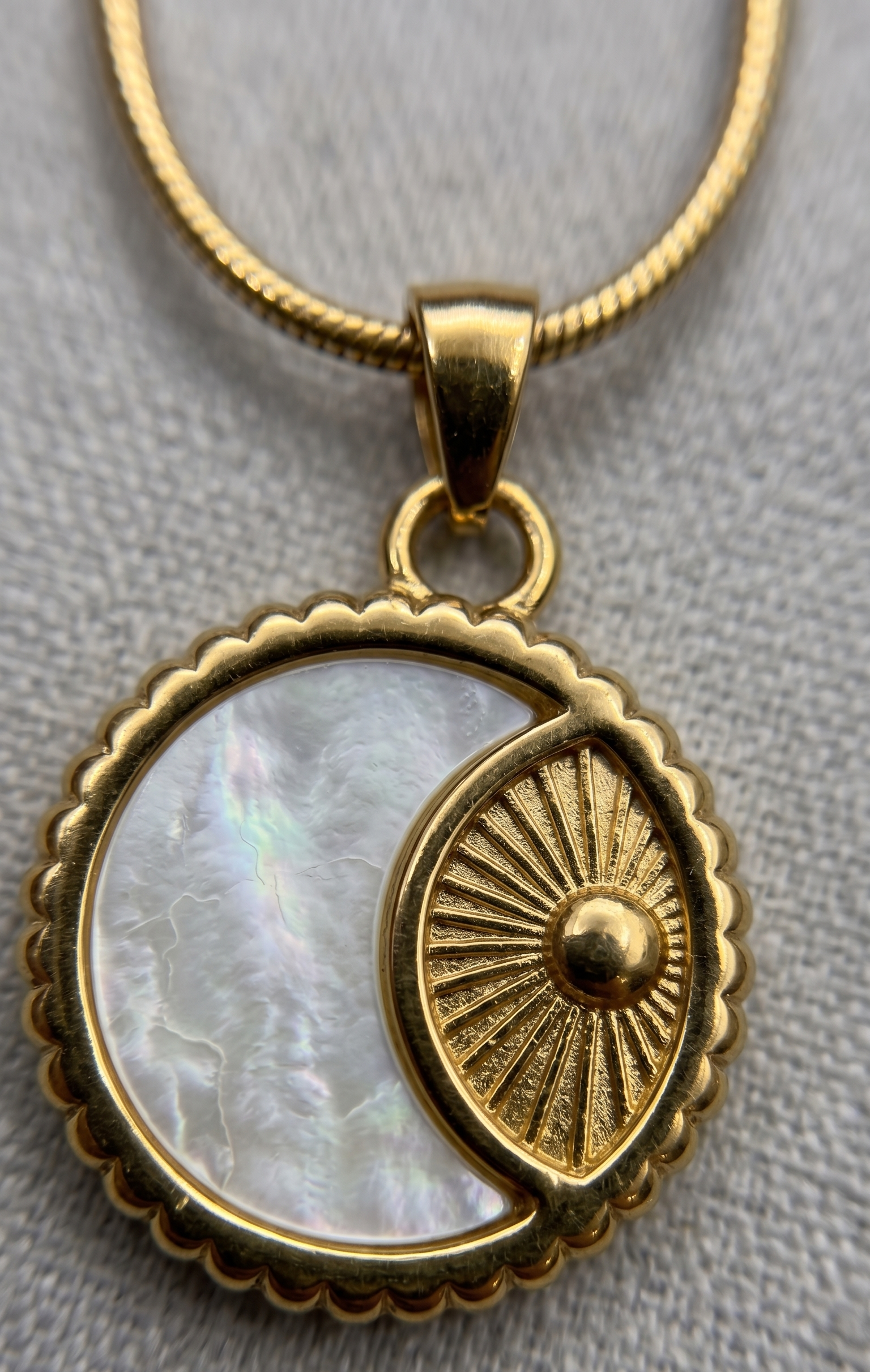 Gold pendant with a circular design on a gray background