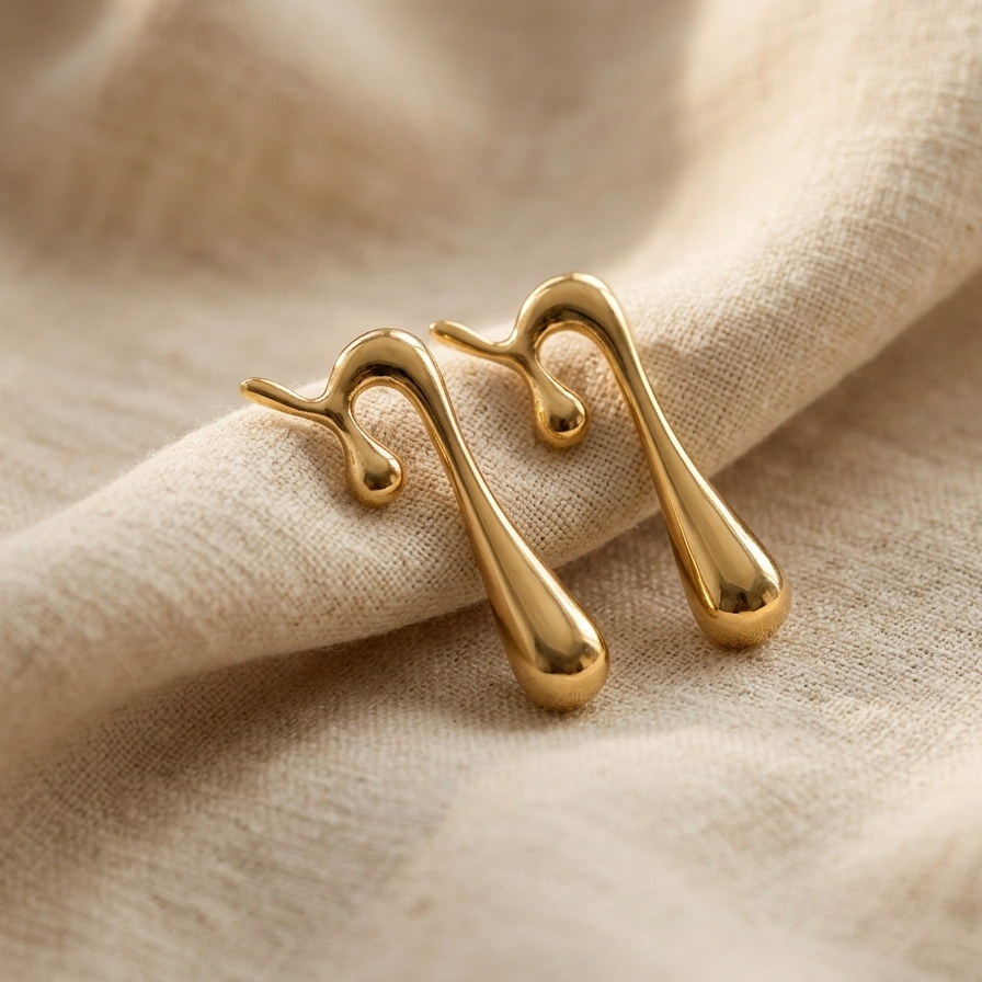 Gold earrings on a beige fabric background