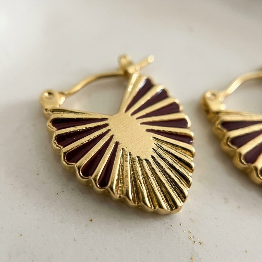 Gold earrings with a sunburst design on a light background