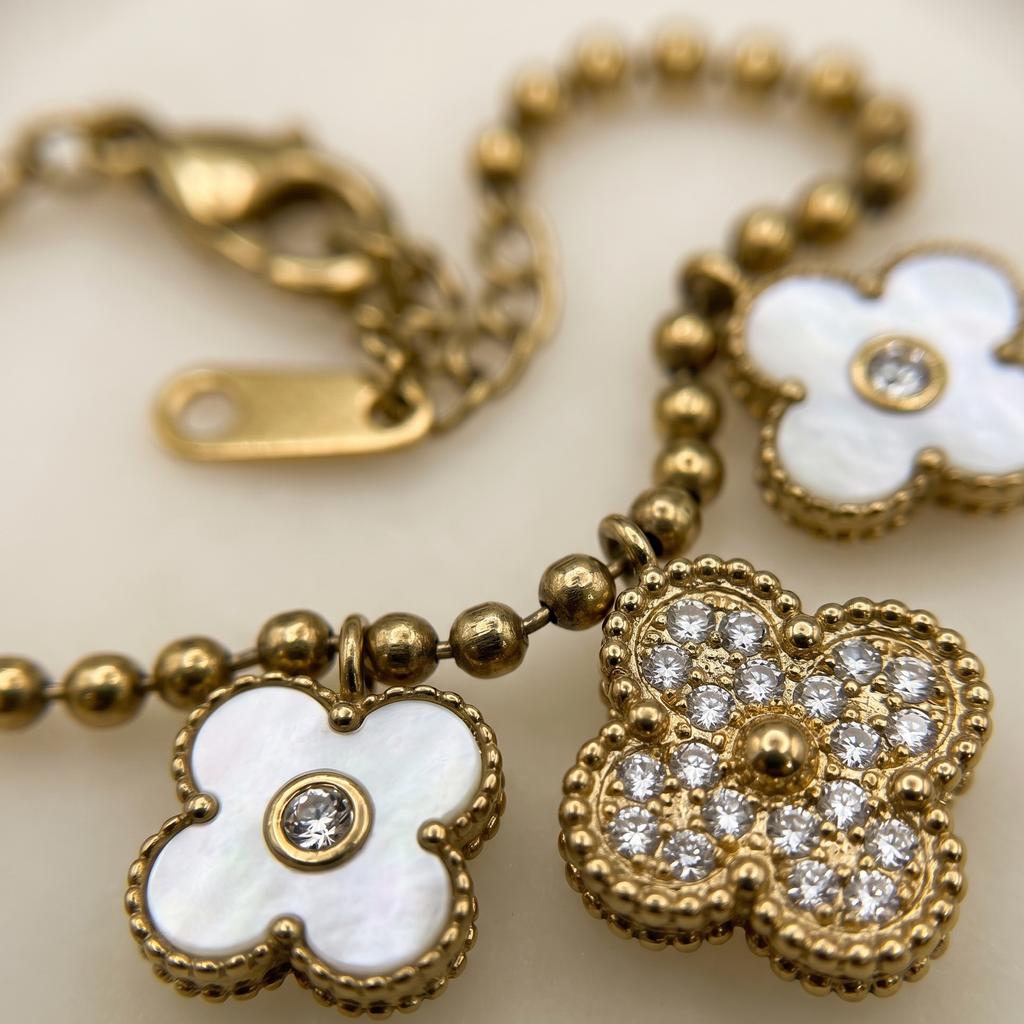 Gold bracelet with white flower charms on a light background