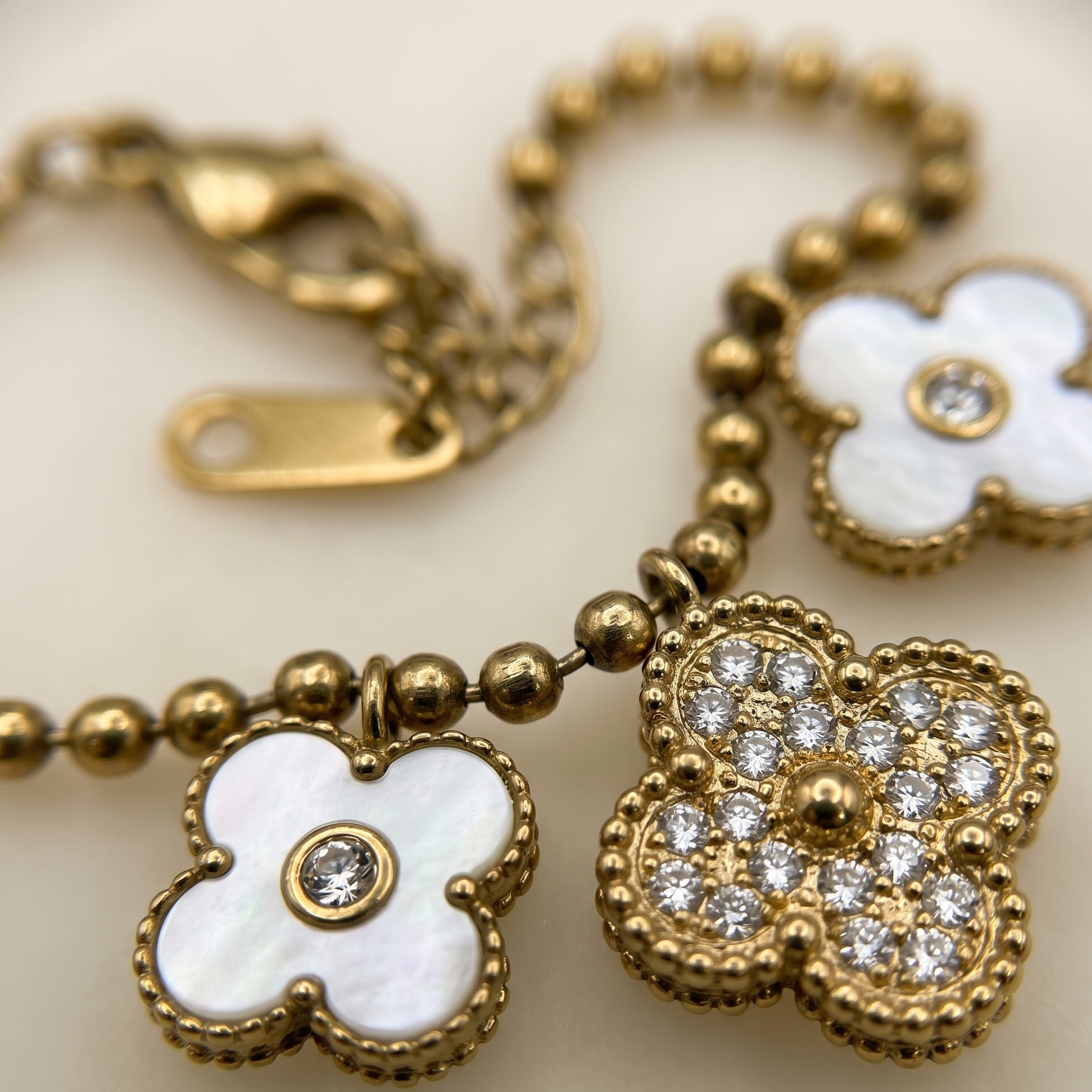 Gold bracelet with white flower charms on a light background