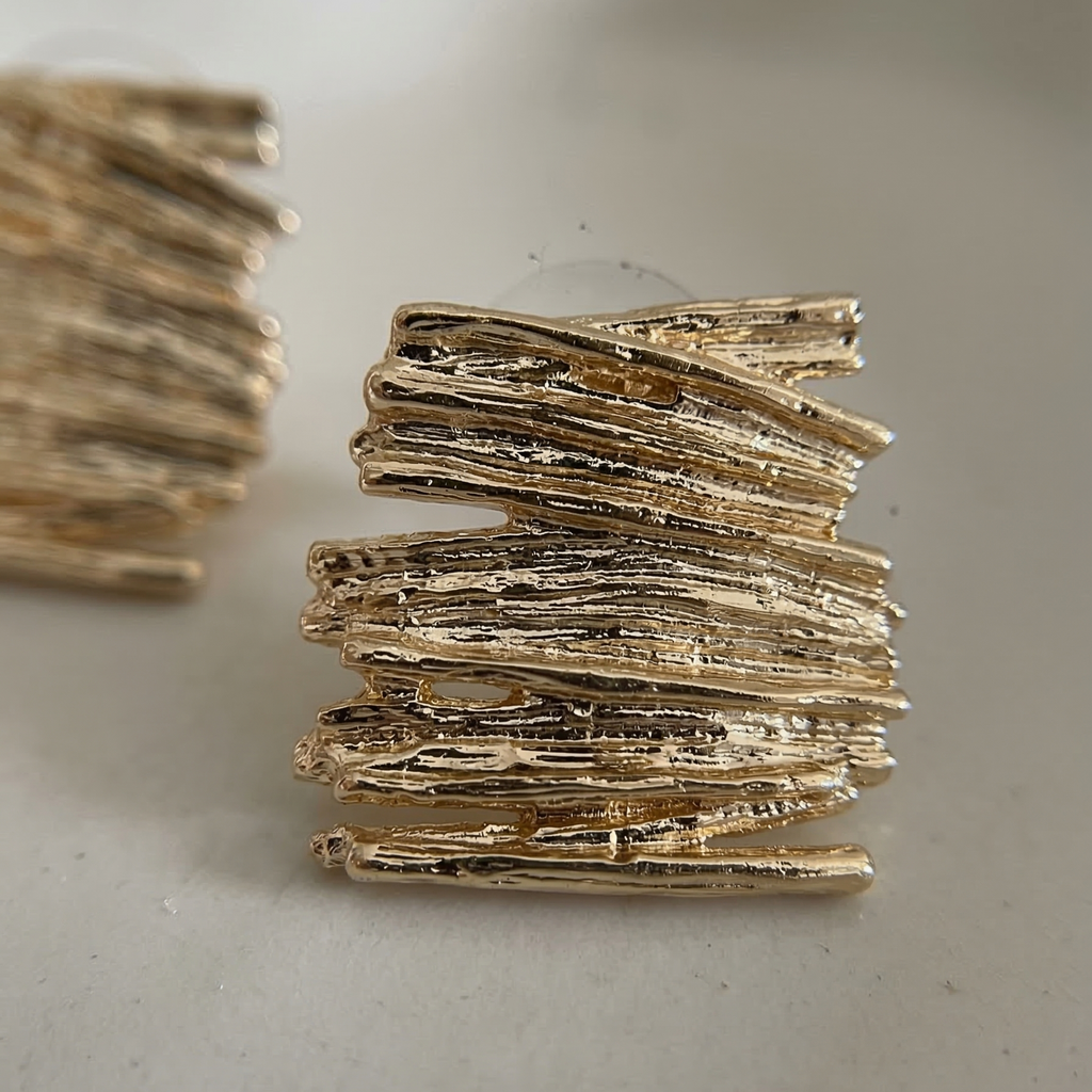 Gold textured earrings on a light gray background
