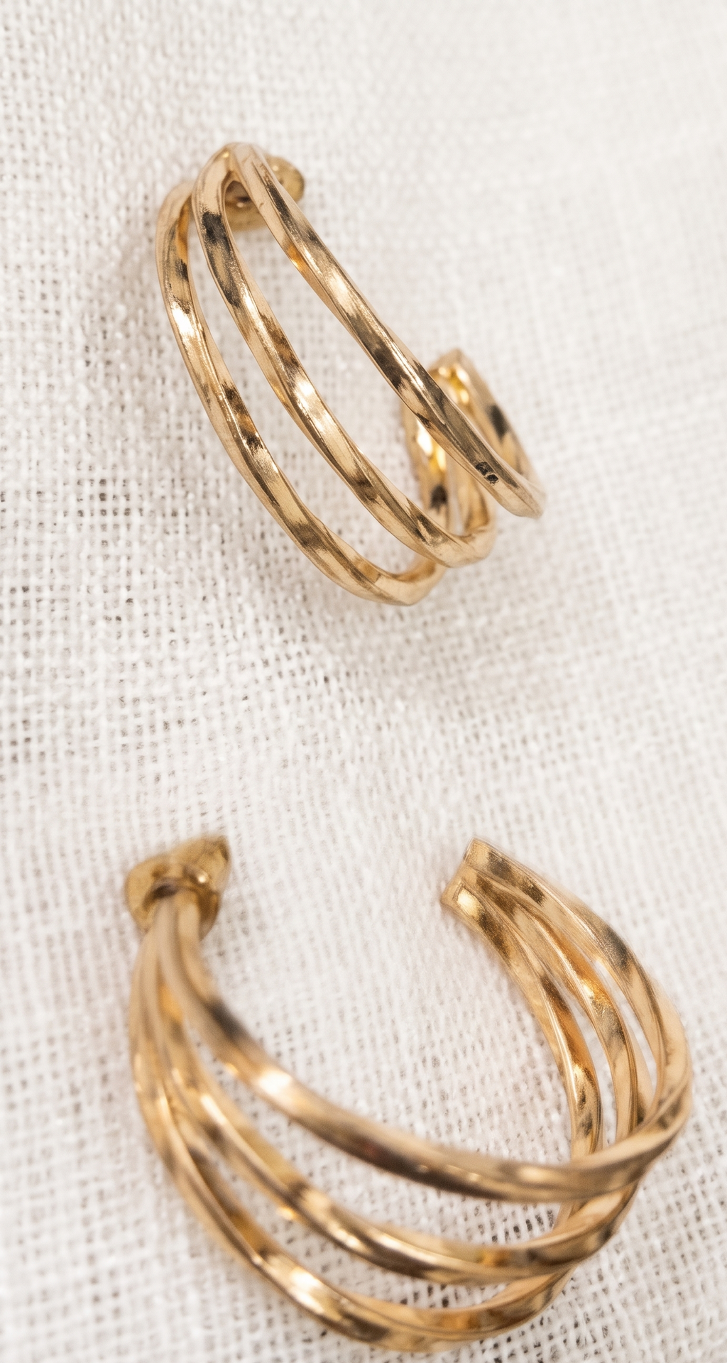 Gold hoop earrings on a textured white fabric background