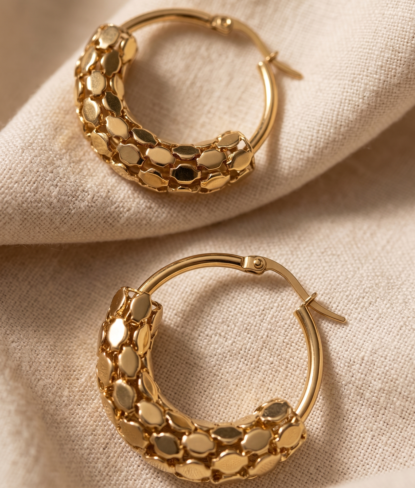 Gold hoop earrings on a beige fabric background