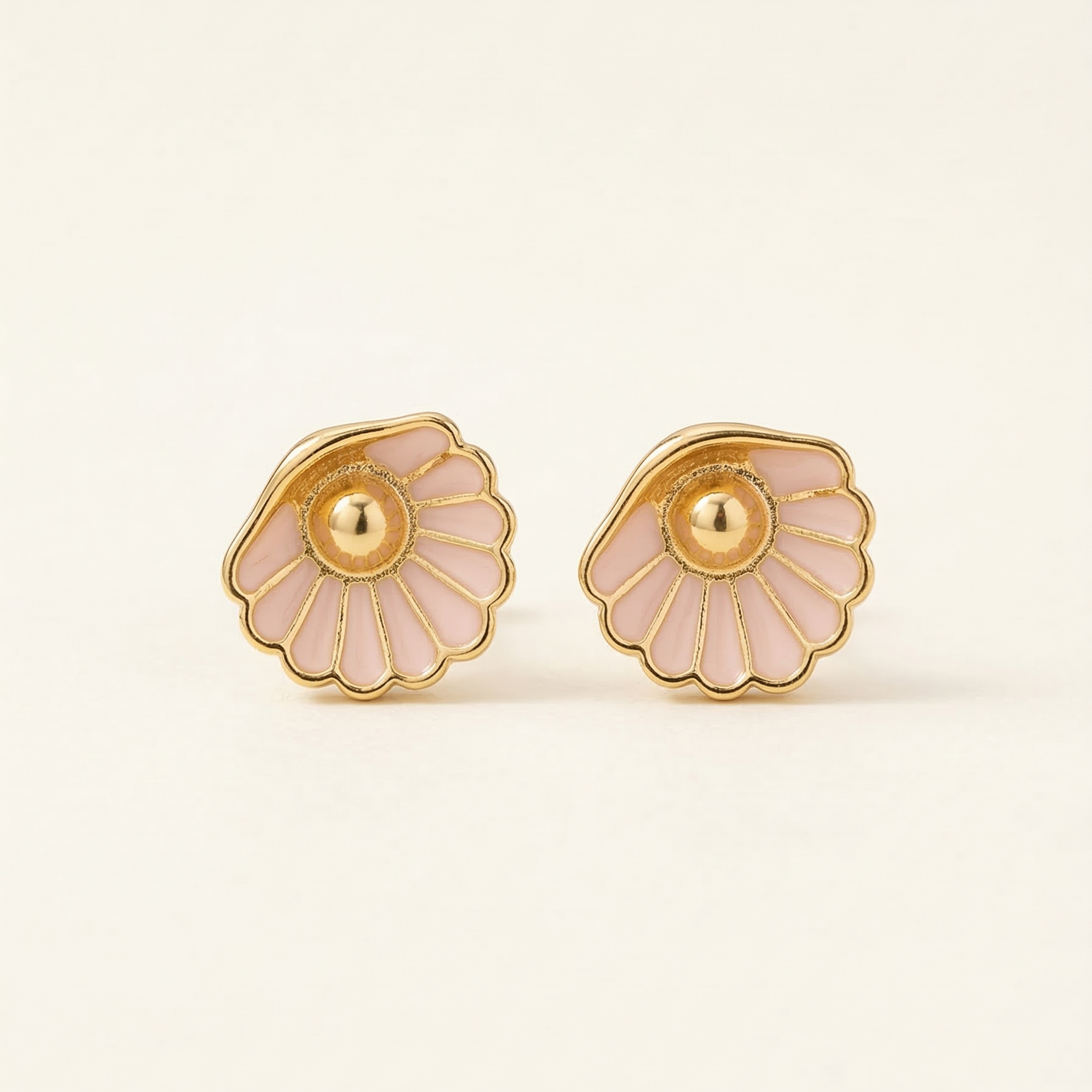 Pair of gold and pink floral earrings on a light beige background