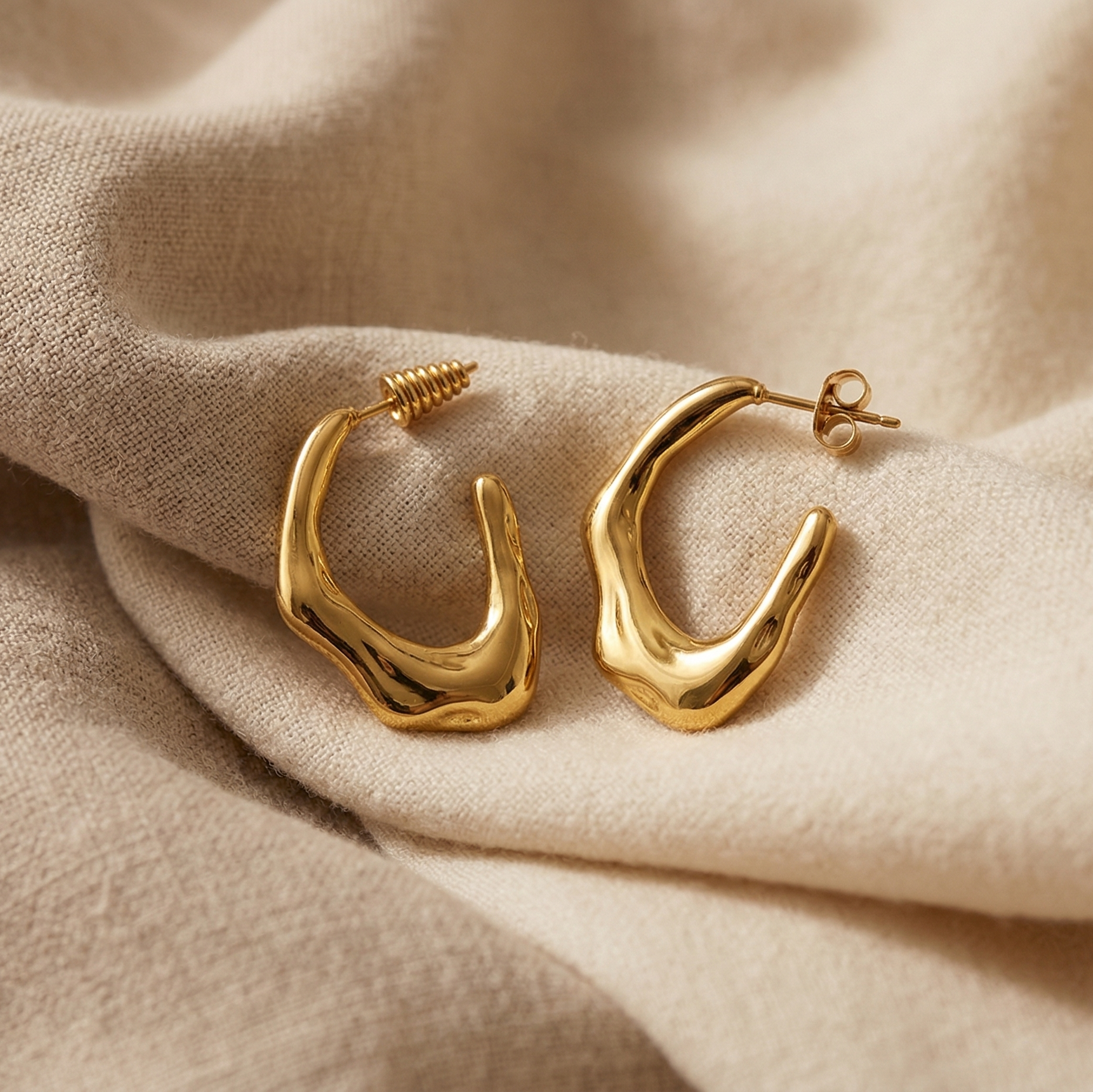 Gold hoop earrings on beige fabric