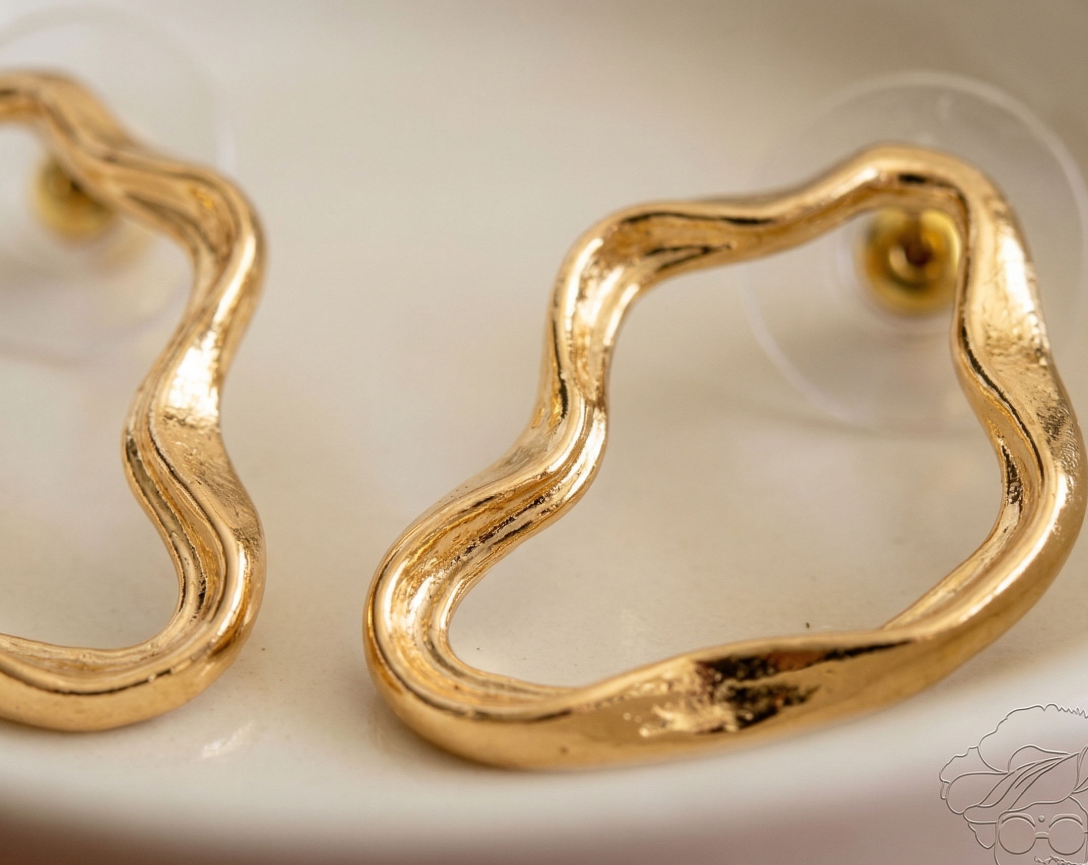Gold hoop earrings on a white dish