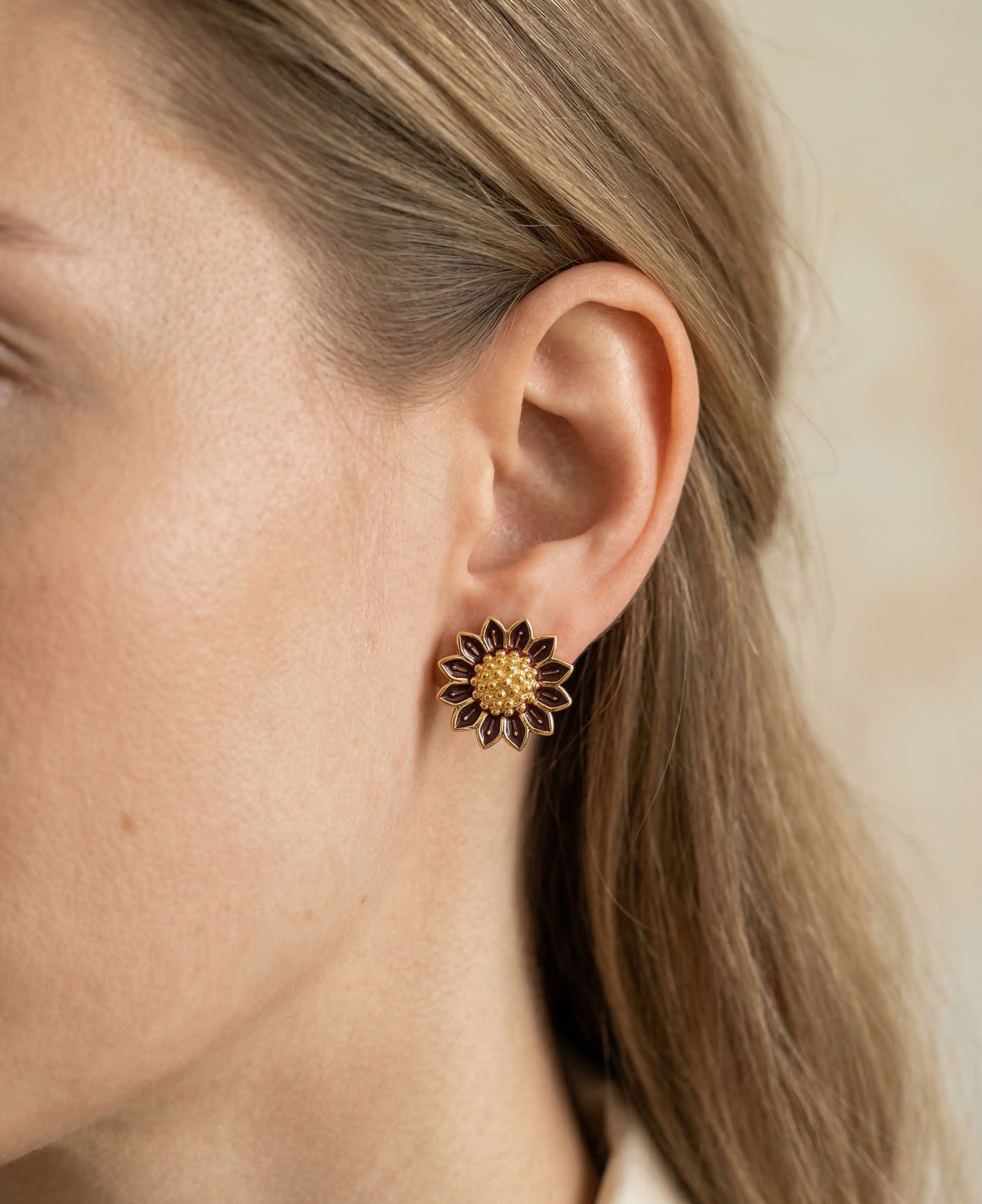Close-up of a person wearing a floral earring with a beige background