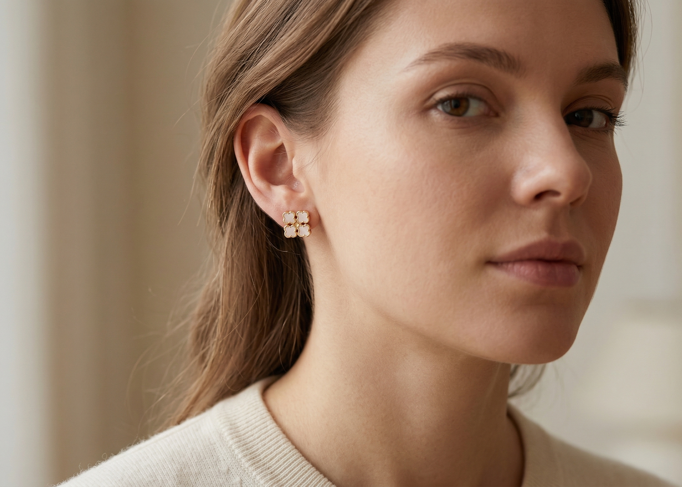 Woman wearing diamond earrings with a neutral background