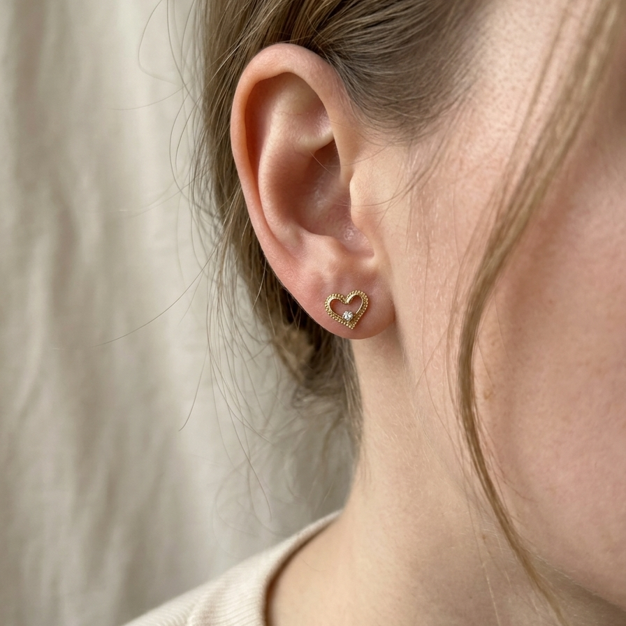 Heart-shaped earring worn by a person with a neutral background