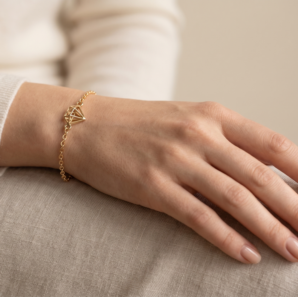 Hand wearing a gold bracelet on a neutral background