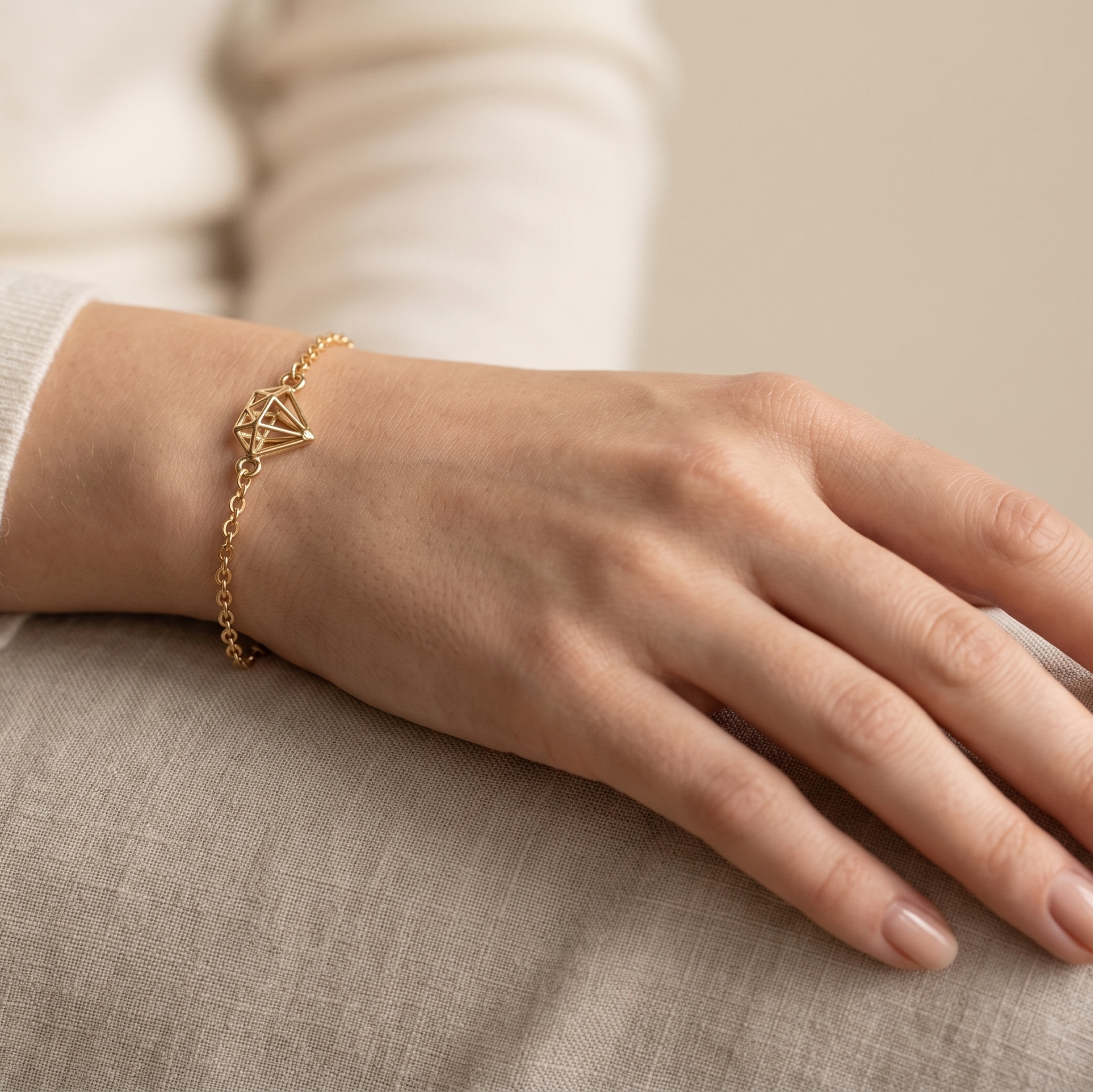 Hand wearing a gold bracelet on a neutral background