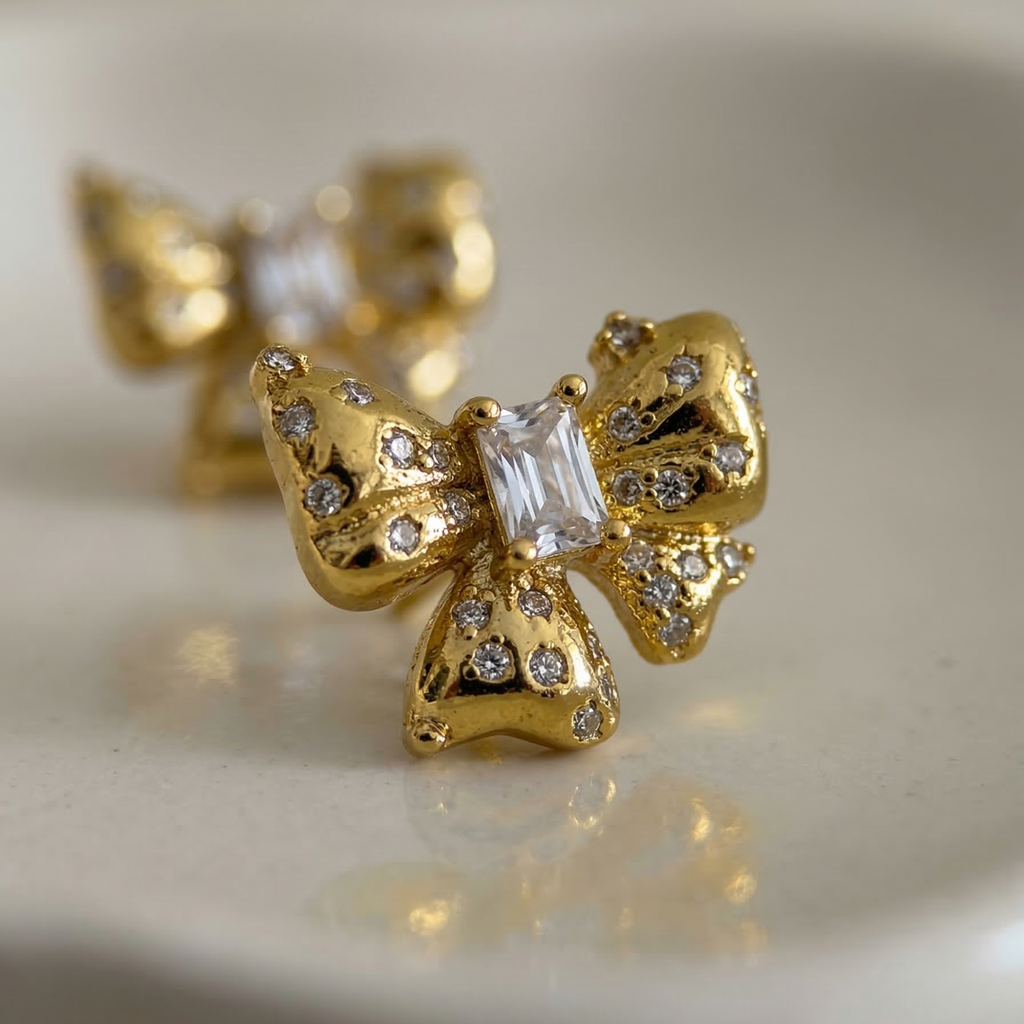 Gold butterfly earrings with clear gemstones on a beige background