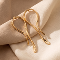 Gold earrings on a beige fabric background