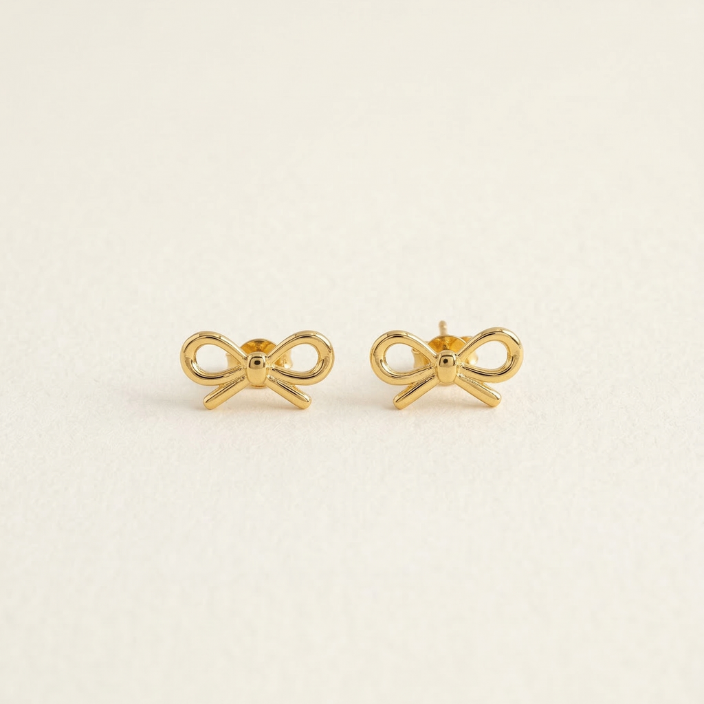 Gold bow-shaped earrings on a light beige background