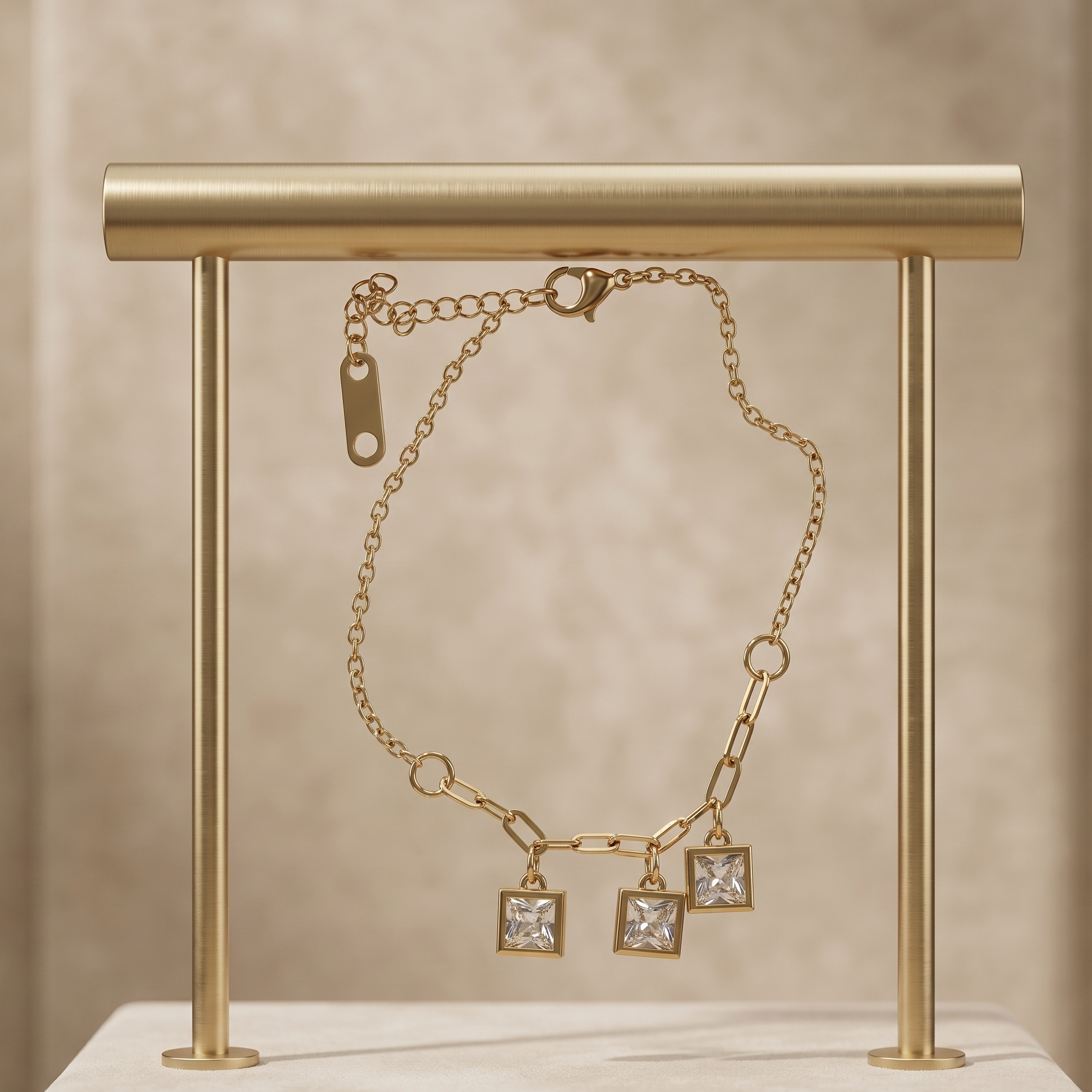 Gold chain necklace with square pendants on a gold stand against a beige background