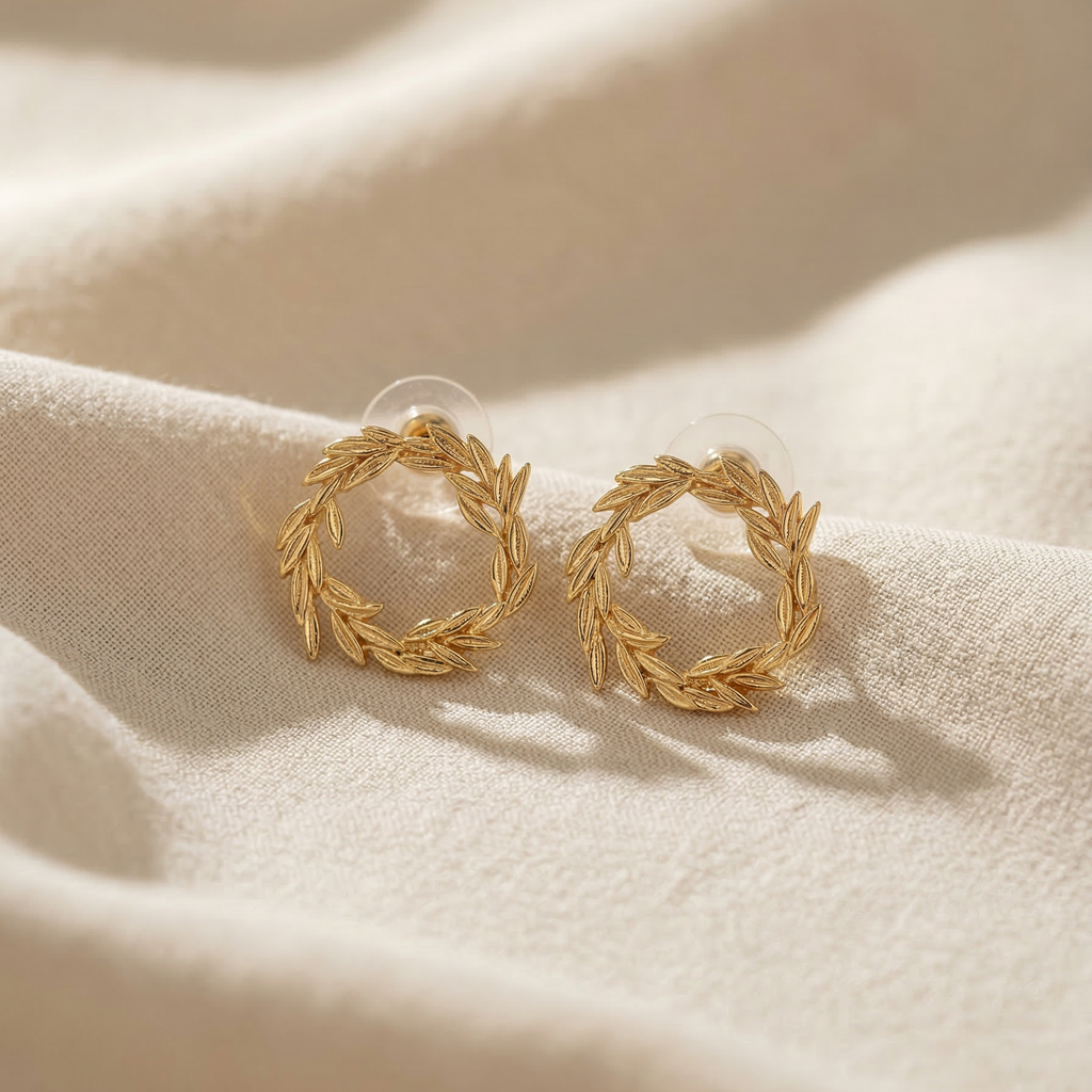 Gold hoop earrings on a beige fabric background