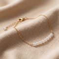 Gold bracelet with pearls on a beige fabric background