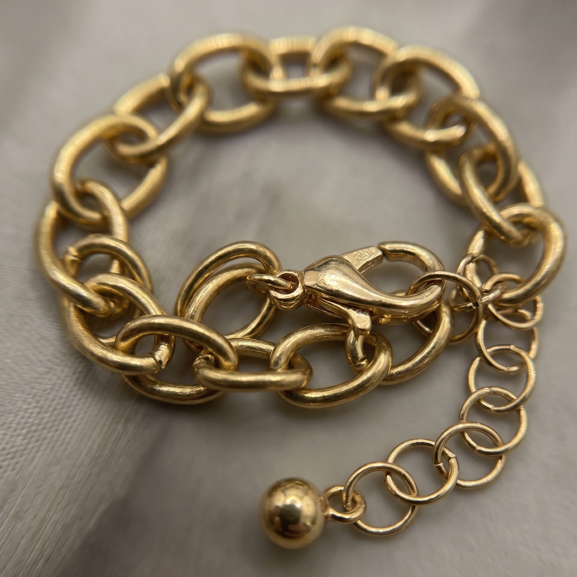 Gold chain bracelet with a clasp on a neutral background