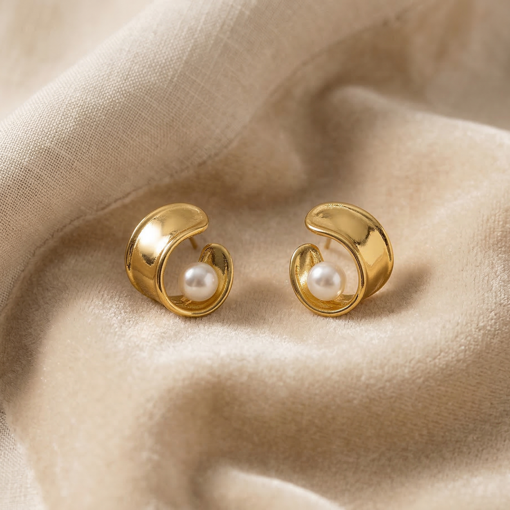 Gold earrings with pearl centers on beige fabric