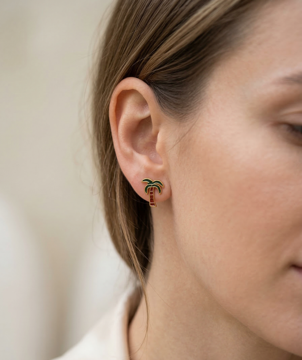 Close-up of a person wearing a small earring with a palm tree design.