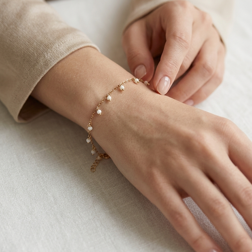 Hand wearing a delicate bracelet on a light background