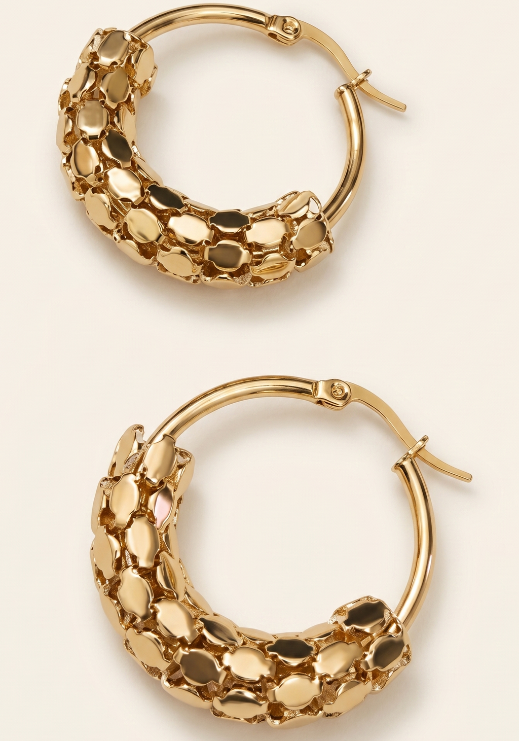 Pair of gold hoop earrings on a beige background