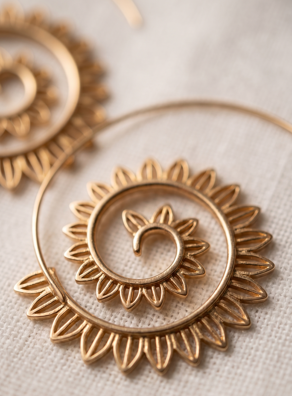 Gold hoop earrings with intricate designs on a light background