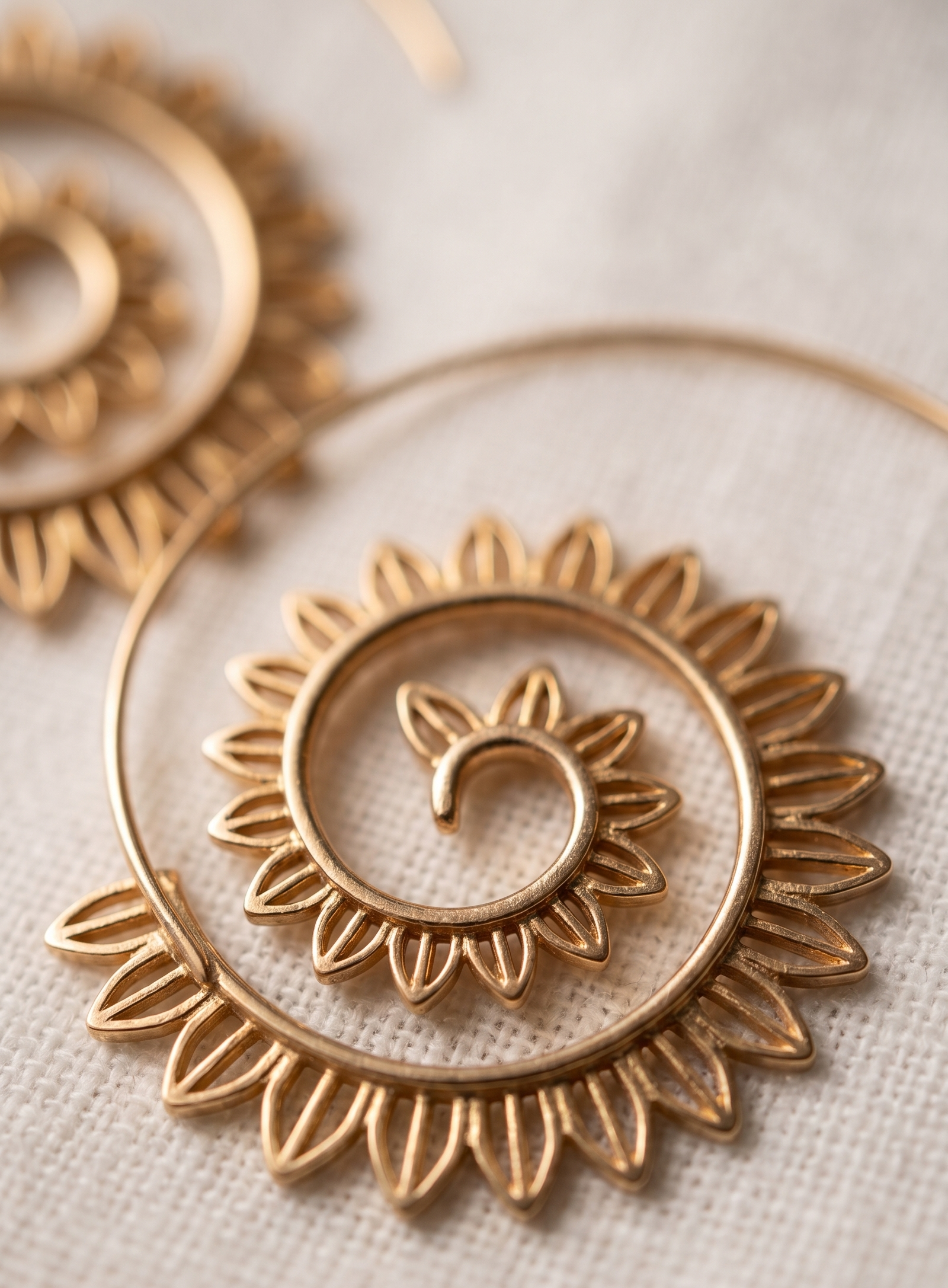 Gold hoop earrings with intricate designs on a light background