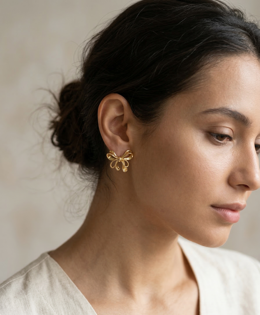 Woman wearing gold earrings with a neutral background