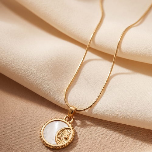 Gold necklace with a circular pendant on a beige fabric background