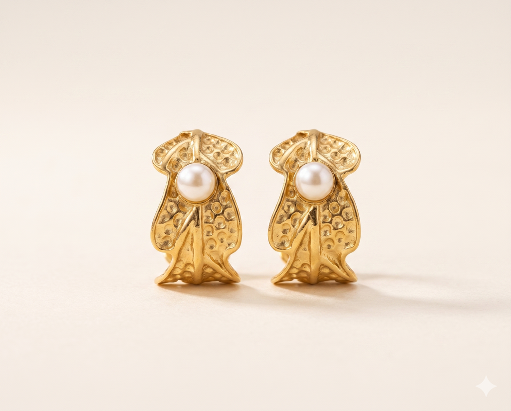 Gold earrings with pearl centers on a beige background